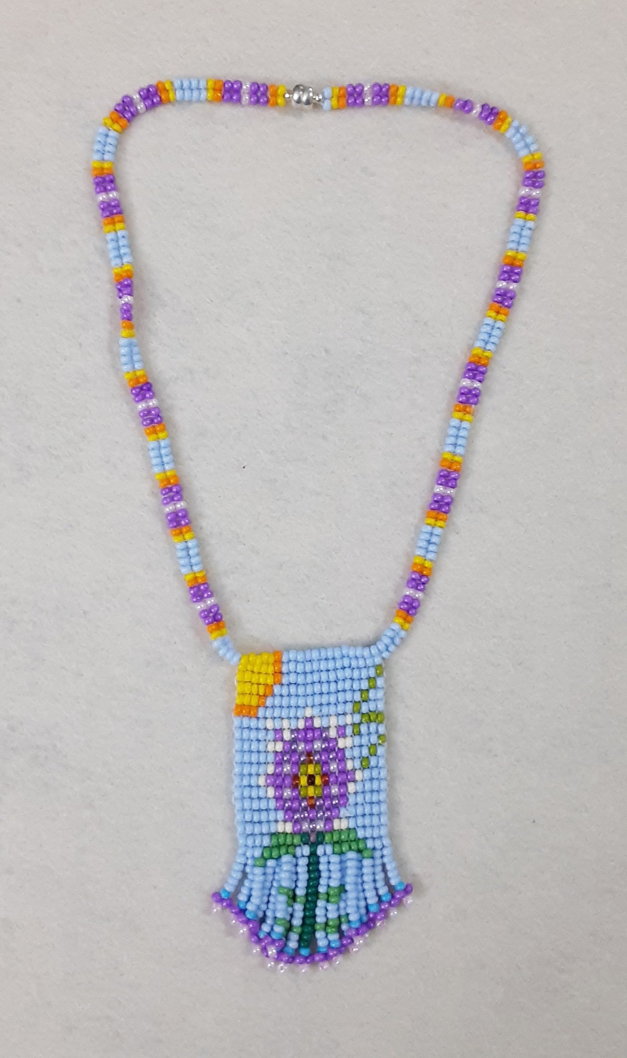 A playful beaded medallion neclace, inspired by a blossom with jagged-edged petals. designed by Kathy, and hand woven by Kathy.