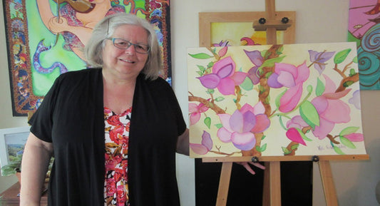 Artist Kathy Poitras, stands by her  naive watercolor painting, Pink Magnolia Tree, in her studio.